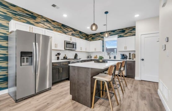 White kitchen with grey details and a mini coffee bar in the corner and grey fridge.