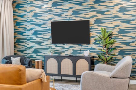 Table with wall-mounted TV and green plant beside it.
