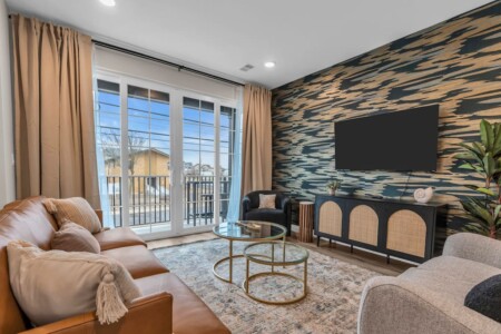 Living room with TV on the wall and a view through the glass door windows.