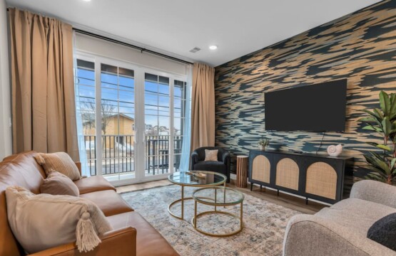 Living room with TV on the wall and a view through the glass door windows.