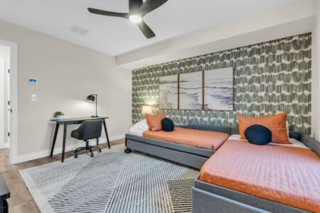 Two single beds with three framed pictures above, plus a side table and chair.