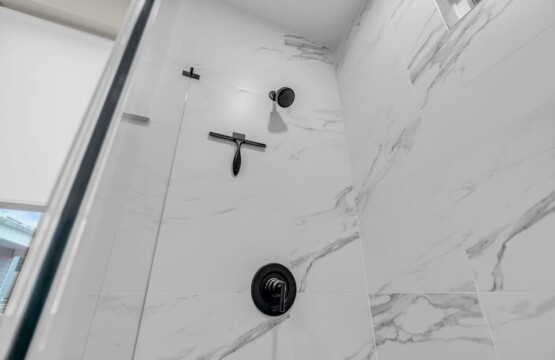 Inside the shower showing clean white tiles.