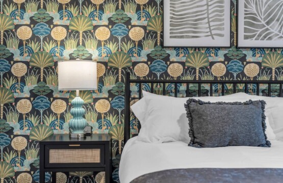 Bedroom bed with green decorative pillows and a side table holding a lamp.