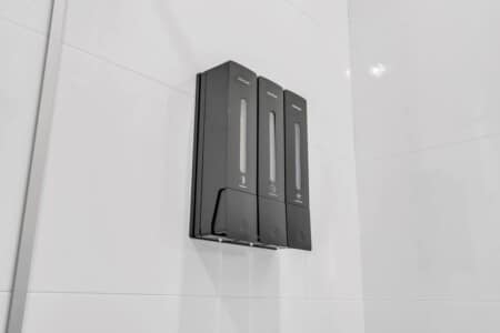 Close-up of three shampoo bottles hanging on the wall in the shower.