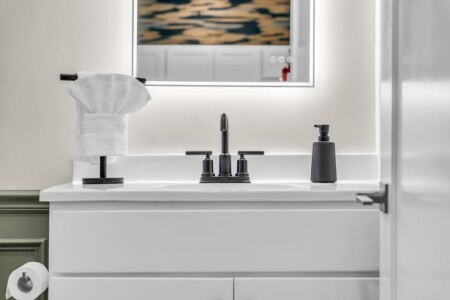 Close-up of a modern bathroom sink, towel on top, and illuminated mirror.