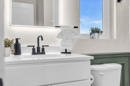 Close-up of a modern bathroom sink, towel on top, and illuminated mirror.
