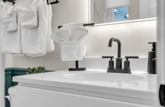 Close-up of a modern bathroom sink, towel on top, and illuminated mirror.