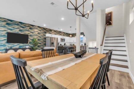 Dining area facing living room and kitchen, with stairs visible in the corner.