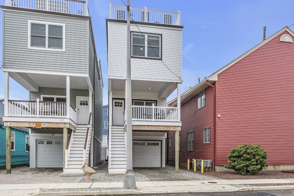 Facing three houses on the street-two white and one red-in a quiet neighborhood.