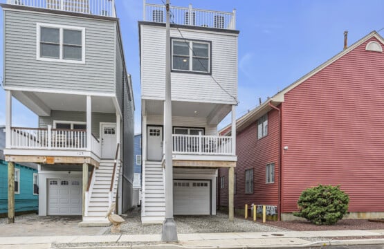 Facing three houses on the street-two white and one red-in a quiet neighborhood.