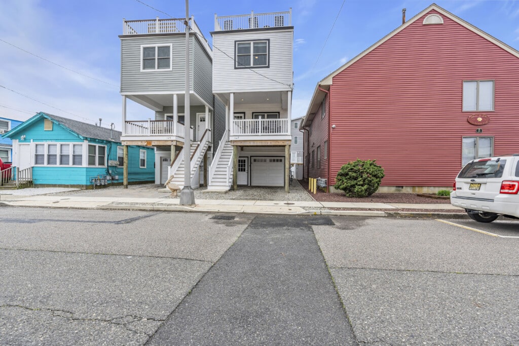 Neighborhood street scene showing two white houses and a red house.