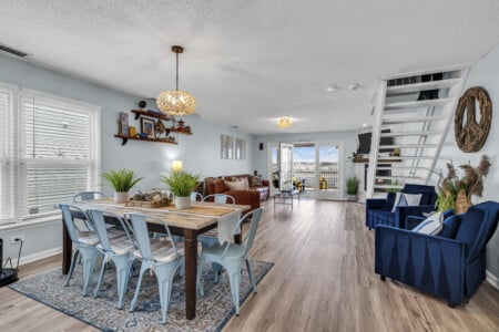 Dining room with living room and stairs in the corner, featuring a waterfront view.