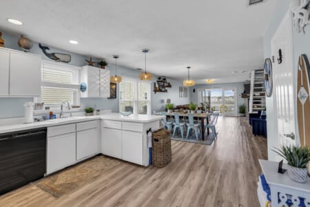 White kitchen opening to living room with large windows showing a waterfront view.