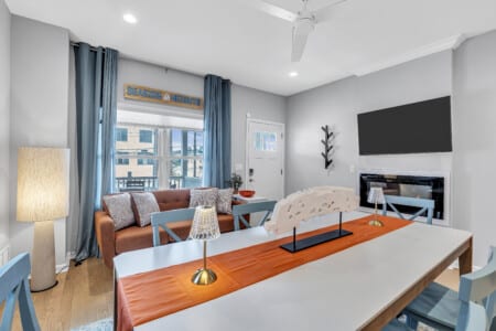 Dining area with large table, tvp placed on the wall, and a big lamp standing in the cornenr.