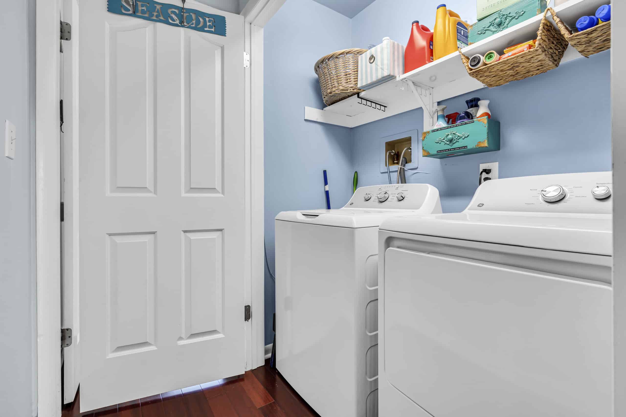 Small laundry room with dryer and washing machine, white dooe and hygiene stuff.