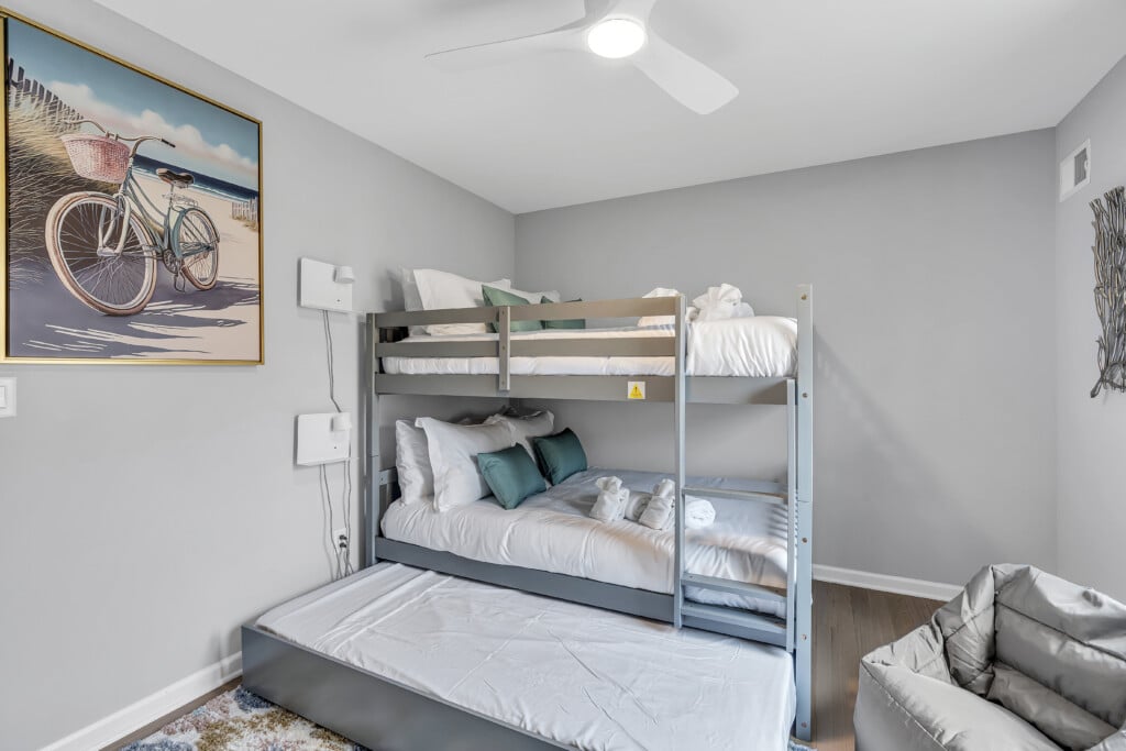 Room with three beds joined together, green pillows, wall art, and a lazy bag on the floor.
