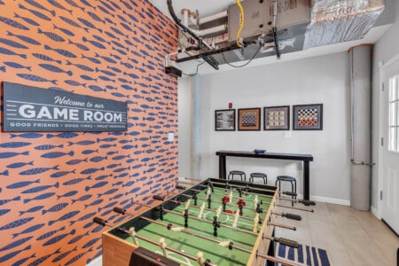 Game room with football table, three chairs and a side table, and various games displayed on the wall.