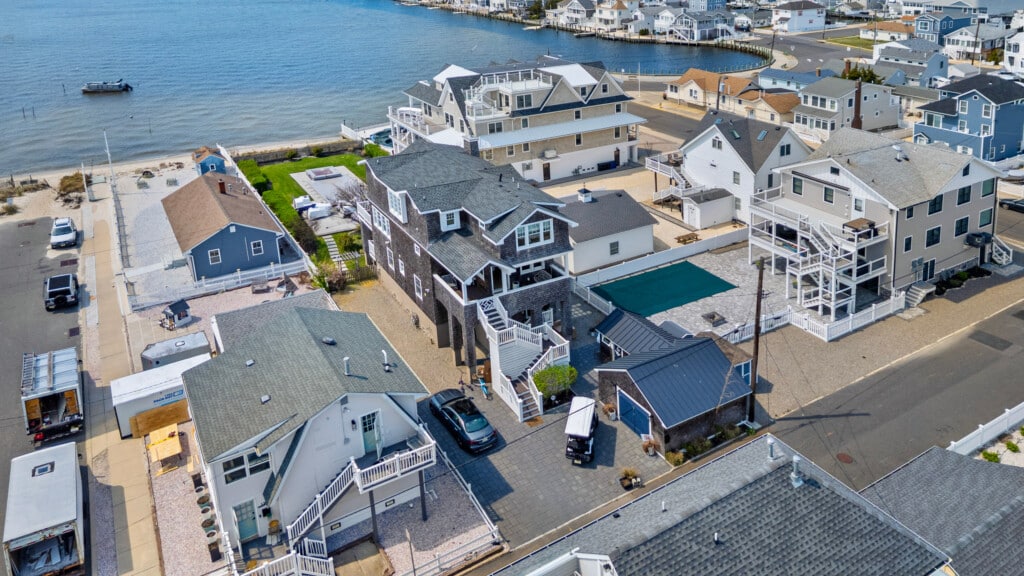 Aerial view of a waterfront Jersey neighborhood with bayside homes and one boat near the shore under clear blue skies.