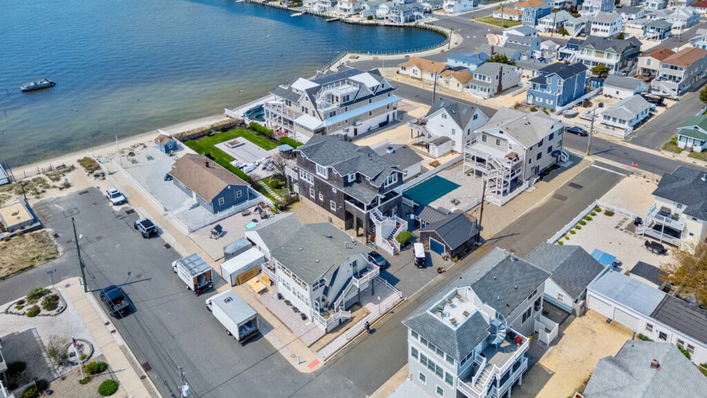 Waterfront neighborhood in Jersey seen from above, featuring bayside vacation homes and a single boat by the shore.
