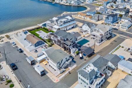 Waterfront neighborhood in Jersey seen from above, featuring bayside vacation homes and a single boat by the shore.