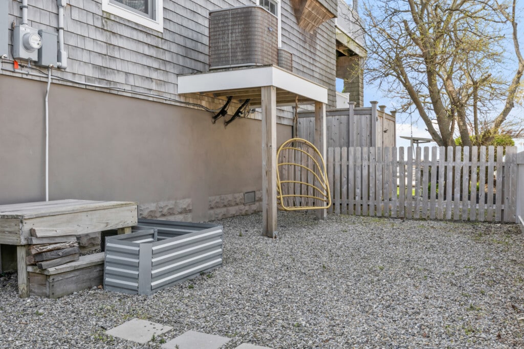 Stone-covered garden with a golden swing, wooden fence, and a beautiful tree creating a peaceful outdoor space.