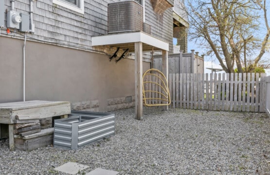 Stone-covered garden with a golden swing, wooden fence, and a beautiful tree creating a peaceful outdoor space.