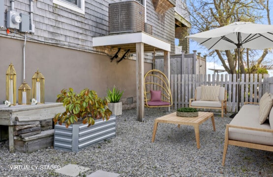 Sunny garden with stone floor, cozy seating, umbrella, and a gold swing with pink pillows.