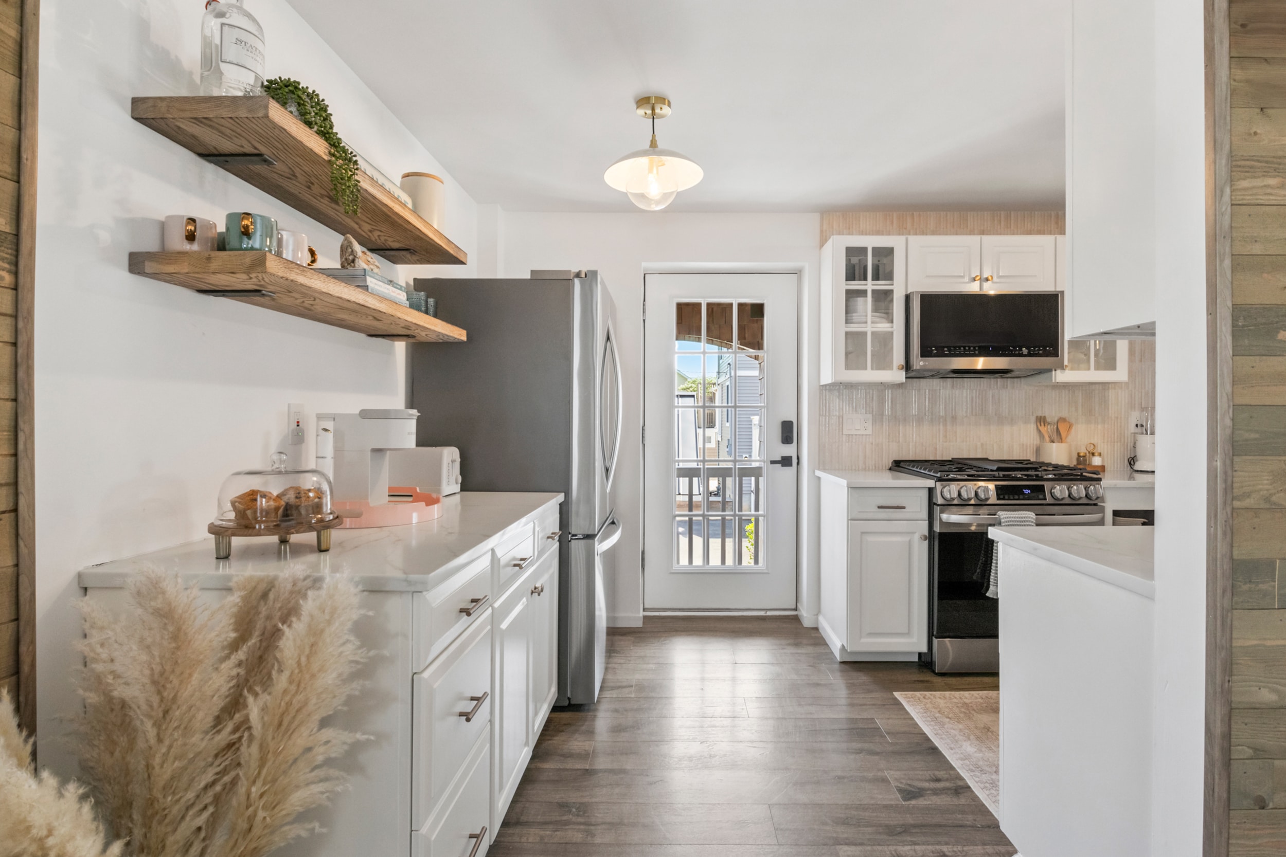 White kitchen with outside door, coffee machine, and muffins on the kitchen table.