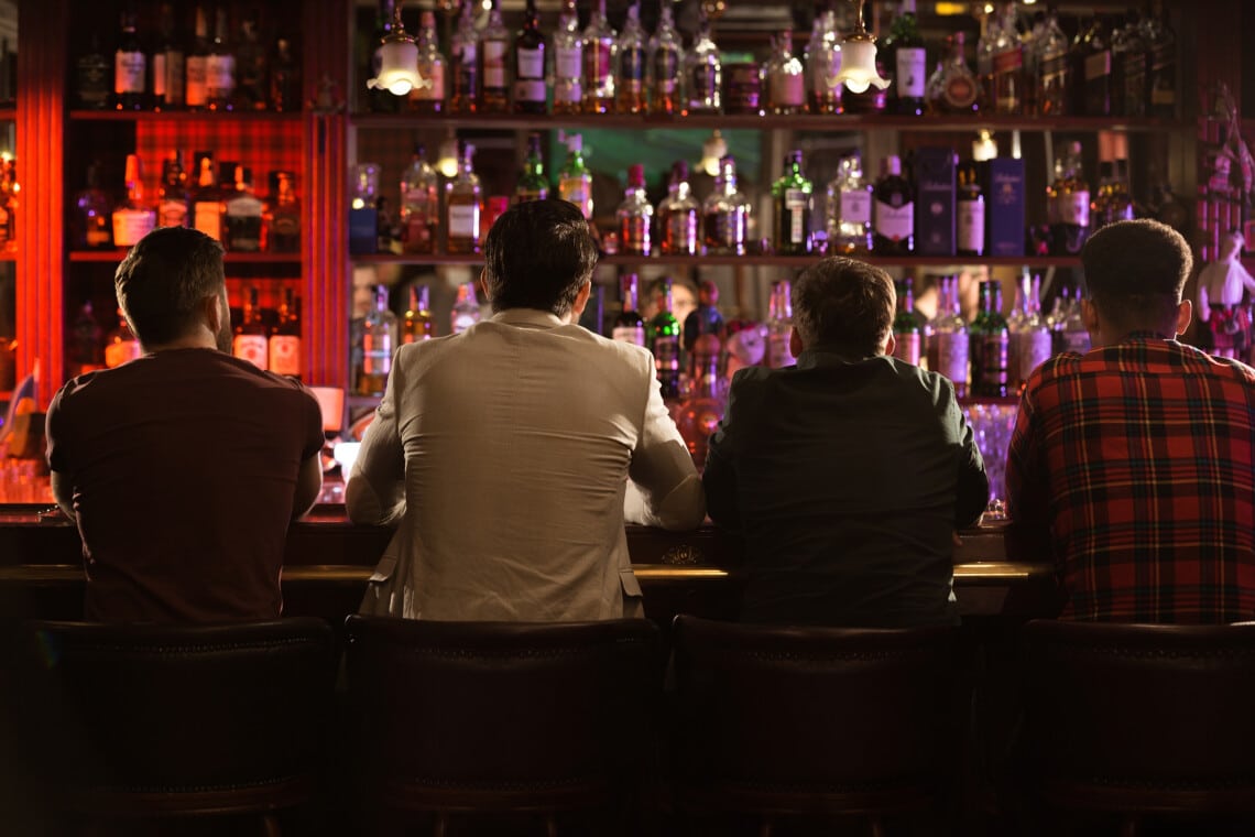 Back view of four young men drinking beer