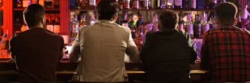 Back view of four young men drinking beer