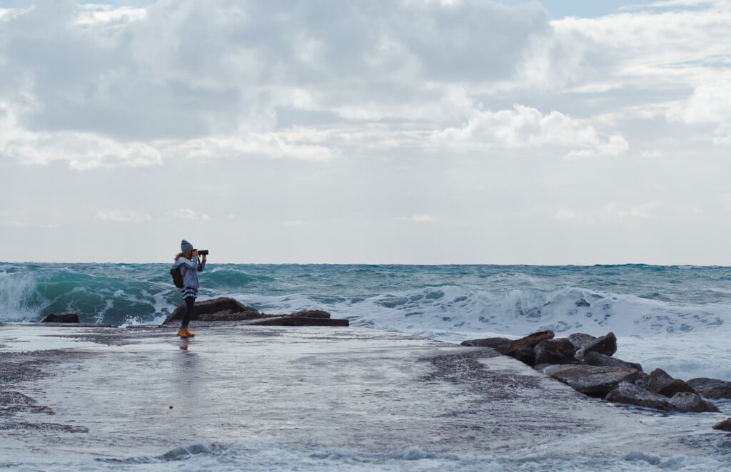 A girl taking photo with camera in beach during daytime with sea on background