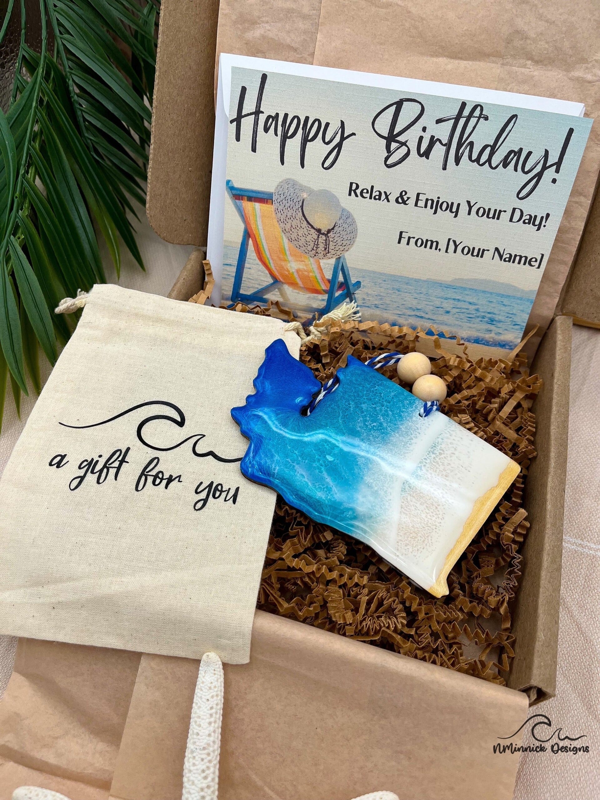 Birthday box with card featuring a sea drawing and a gift shell beside it.|Sunny Jersey street with people walking and various stores lining the road.|Close-up view of a store in a Jersey neighborhood.|Jersey town houses decorated with large logos of Puma