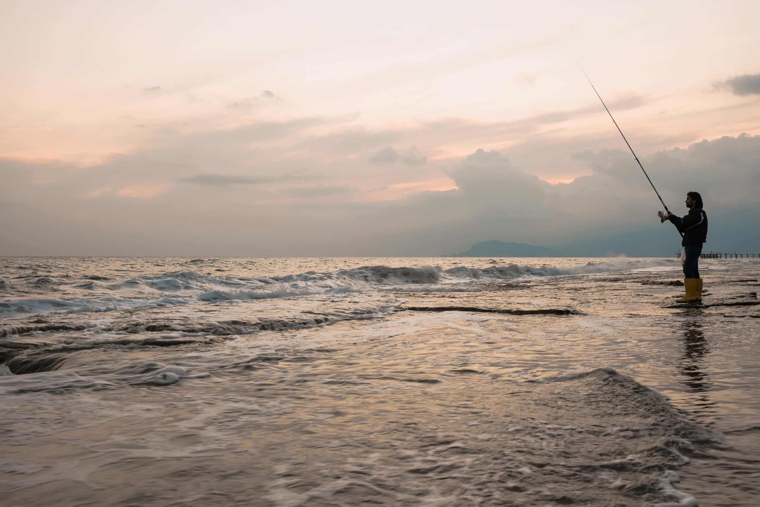 Man fishing on the sea shore|several fishing rods in a row on the beach|Man fishing on the sea shore|A girl taking photo with camera in beach during daytime with sea on background