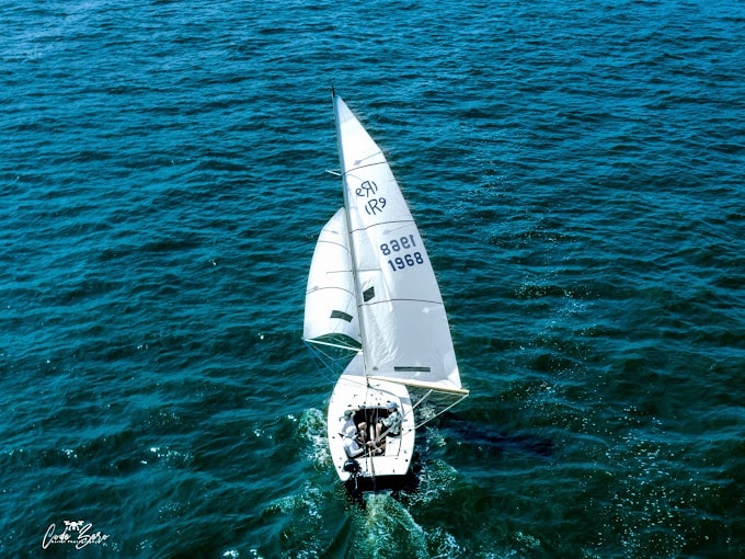 boat displaying numbered flag on a calm waterfront.|Empty Toms River Yacht Club with boats docked around the club.|Full view of people gathering near Toms River Yacht Club in a Jersey neighborhood.|Waterfront view during a colorful sunset in Jersey.|Group of small boats displaying numbered flags on a calm waterfront.