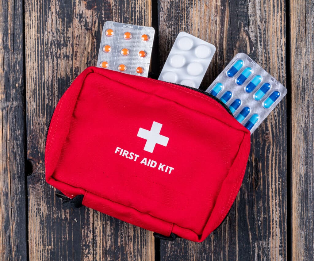 first aid kit with pills top view dark wooden background