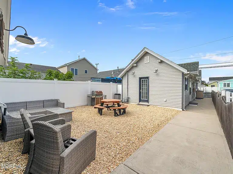 Outdoor patio area of a duplex at 263 Kearney Avenue, Seaside Heights, NJ, featuring seating arrangements, a picnic table, and a fenced yard, ideal for short-term rental guests.